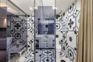 Ein modernes Badezimmer mit gemusterten Fliesen, einer Glasabtrennung und einer sichtbaren Toilette.