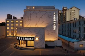 Ein Hotel mit modernem Design, das durch eine markante, geschwungene Fassade und einen gut beleuchteten Eingang gekennzeichnet ist.