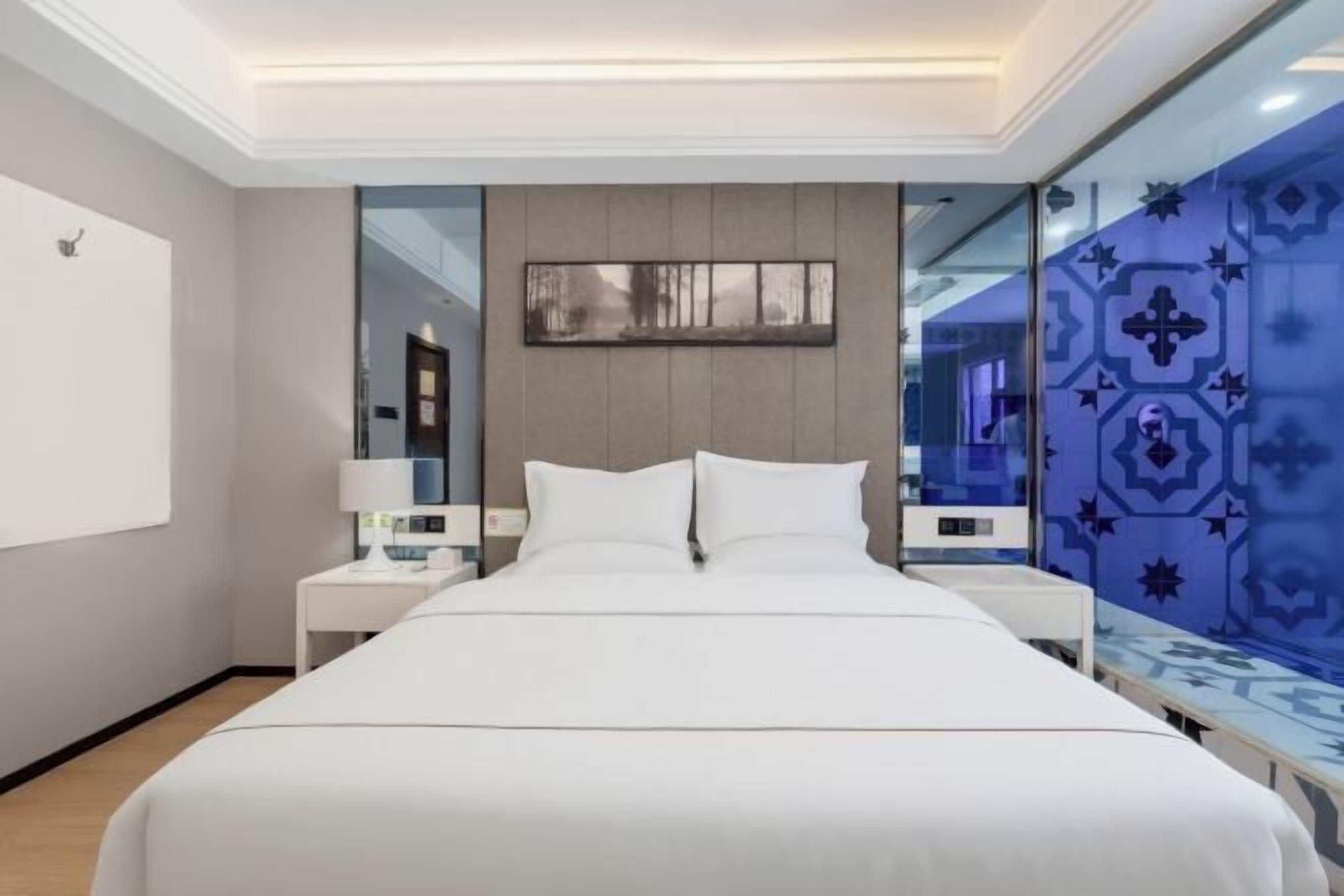 Ein modernes Hotelzimmer mit einem großen Bett, Nachttischen, einem Spiegel und einer dekorativen Wandverkleidung.