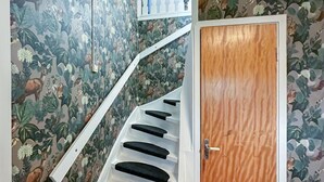 A staircase with black steps and a white handrail, leading to a wooden door with a metal handle. - 3 bedroom gorgeous home in Forserum (Forserum)