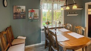 A dining room with a wooden table, chairs, and a window with a view of greenery. - 3 bedroom gorgeous home in Forserum (Forserum)