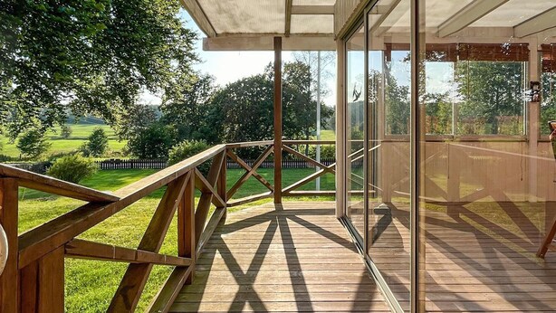 A wooden deck with a glass balustrade overlooking a grassy area. - 3 bedroom gorgeous home in Forserum (Forserum)