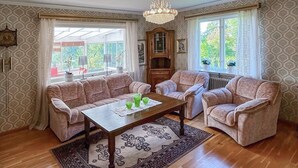 A living room with a sofa set, a coffee table, a chandelier, and patterned wallpaper. - 3 bedroom gorgeous home in Forserum (Forserum)