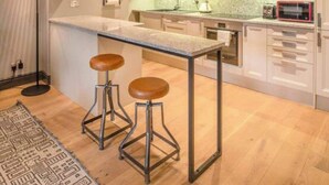 A modern kitchen with a central island, bar stools, and a pendant light.