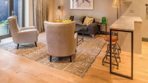 A modern living room with a sofa, armchairs, a coffee table, and a dining area with a bar stool.