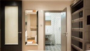 A hotel room with a large wardrobe, a mirror, and a bathroom visible through an open door.