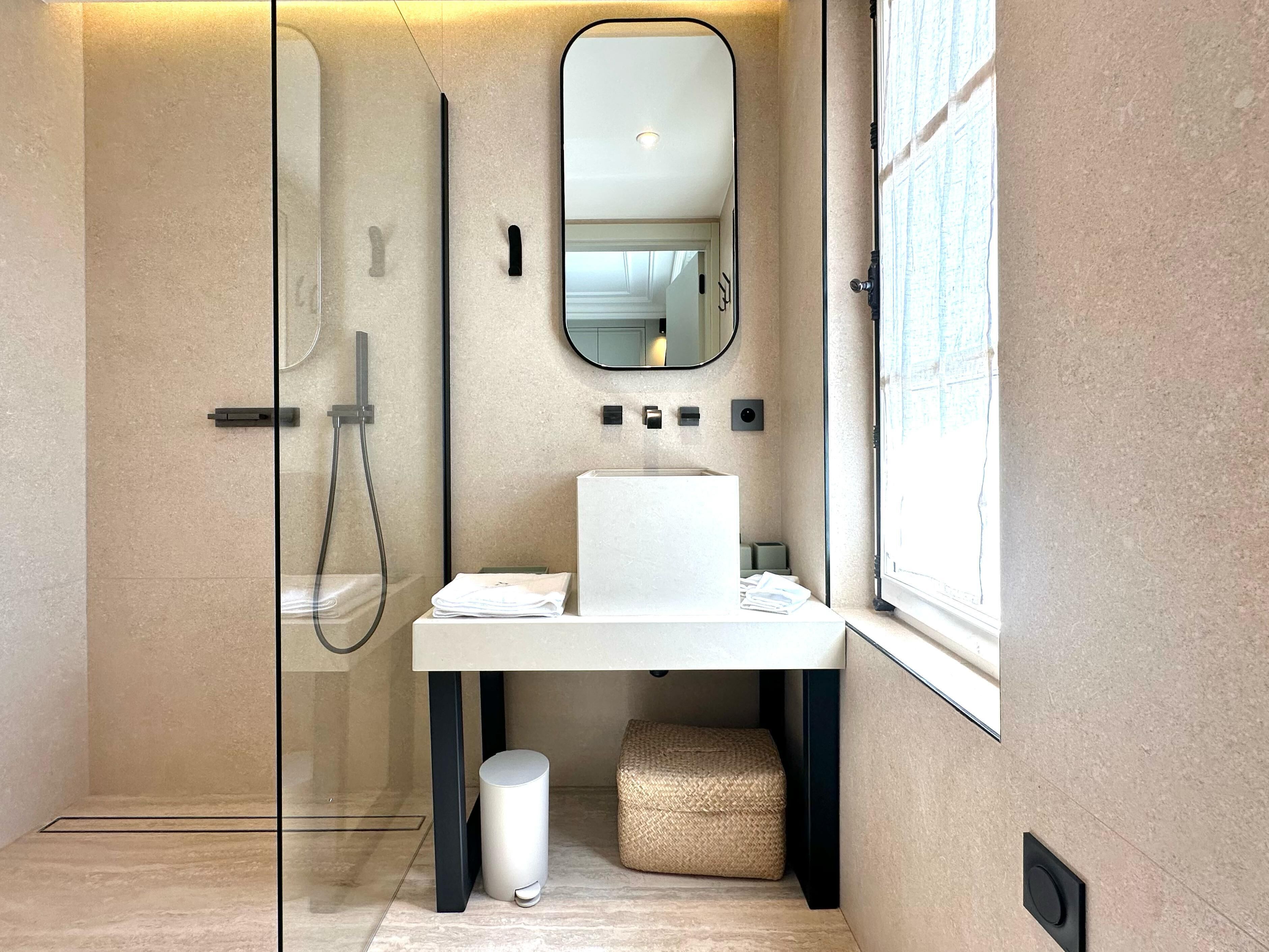 A modern bathroom with a glass-enclosed shower, a white sink, and a large mirror.