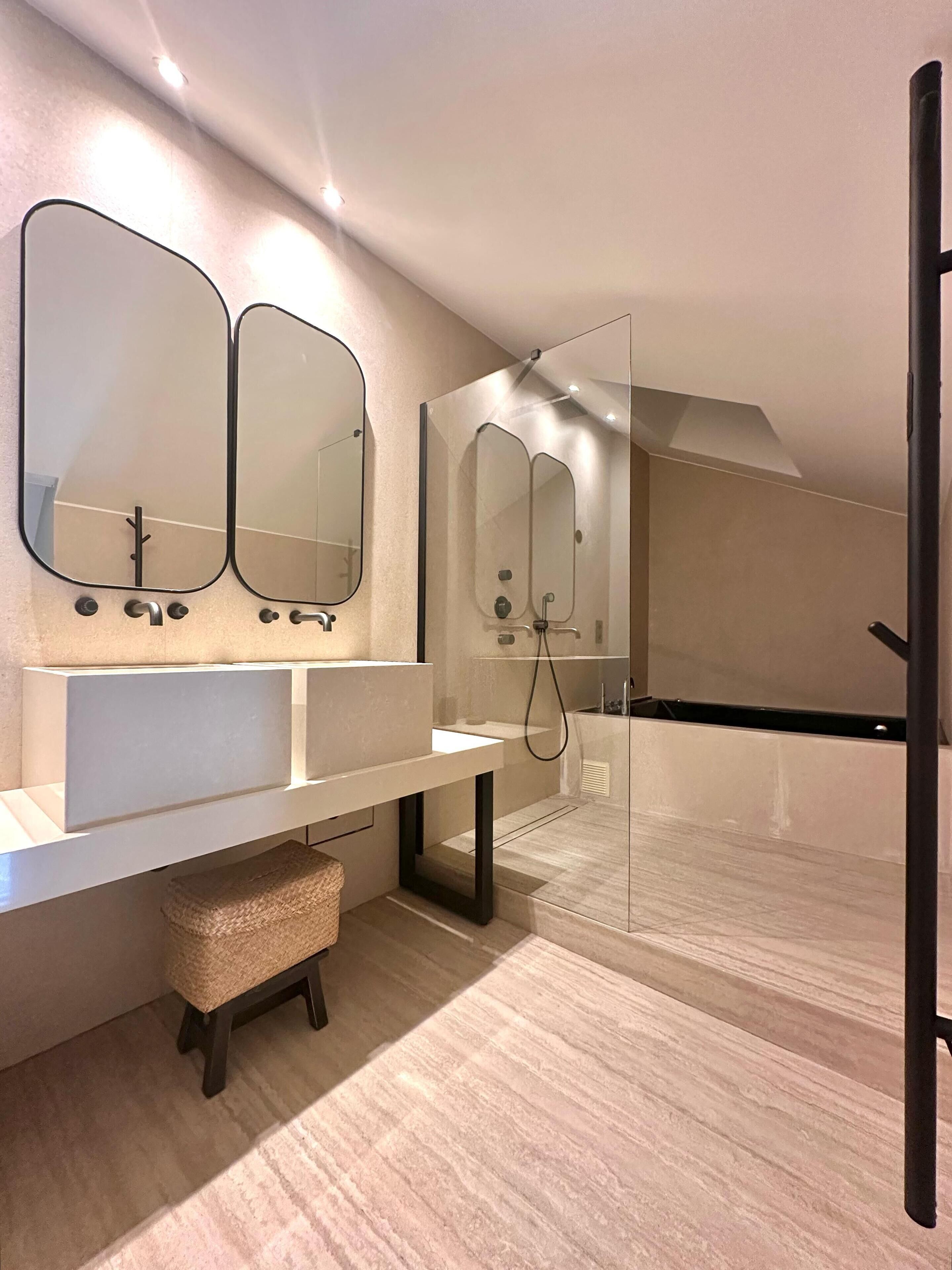 Un baño moderno con un espejo grande, un lavamanos y una zona de ducha.
