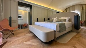 A modern hotel room with a large bed, a seating area with chairs, and a view of the city through the window. - Chateau Pimo (Draguignan)
