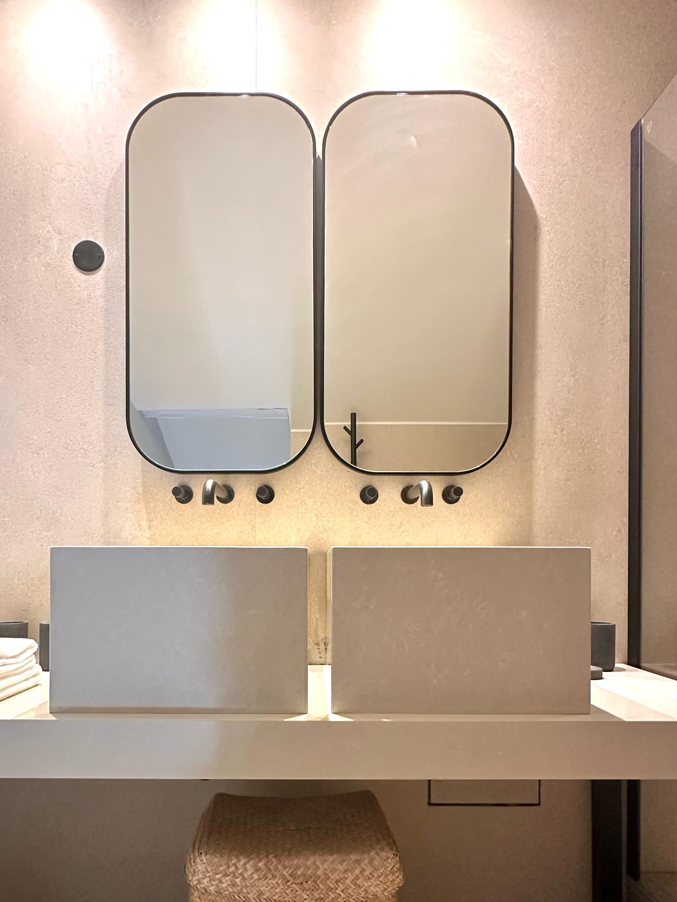 A modern bathroom with two sinks, a towel rack, and a mirror.