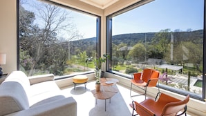 A modern living room with a large window, a sofa, a small table, and two chairs. - Chateau Pimo (Draguignan)