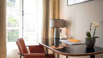 Una habitación moderna con una mesa de vidrio, un sillón de cuero marrón, una lámpara, una orquídea en maceta y un cuadro en la pared.