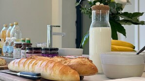 A kitchen counter with a loaf of bread, a bowl, and various condiments. - Chateau Pimo (Draguignan)
