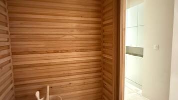 A wooden sauna room with a bench and a wooden bucket.