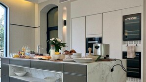 A modern kitchen with a marble island, built-in appliances, and a unique ceiling light fixture. - Chateau Pimo (Draguignan)