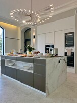Una cocina moderna con una isla de mármol, electrodomésticos integrados y una lámpara de techo original.