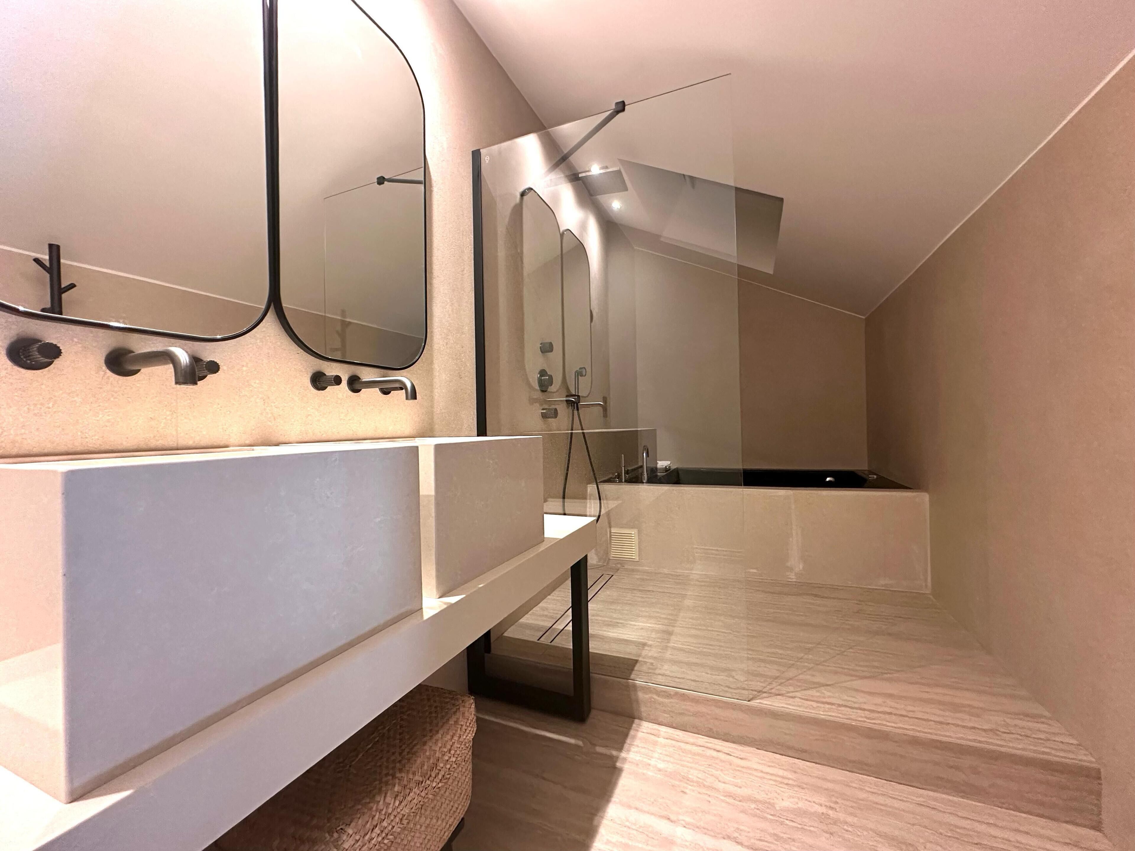 A modern bathroom with a large mirror, a sink, and a bathtub.