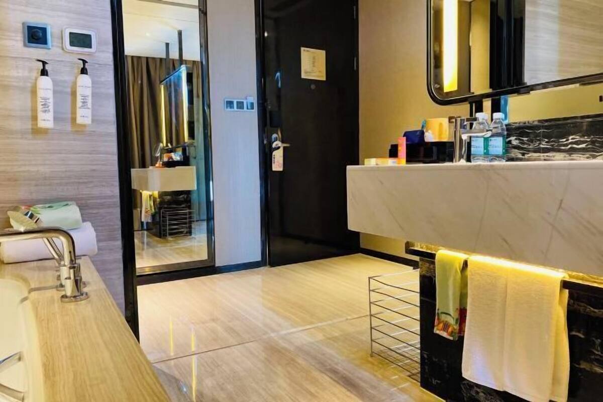 A modern bathroom with a marble countertop, a sink, a mirror, and a towel rack.