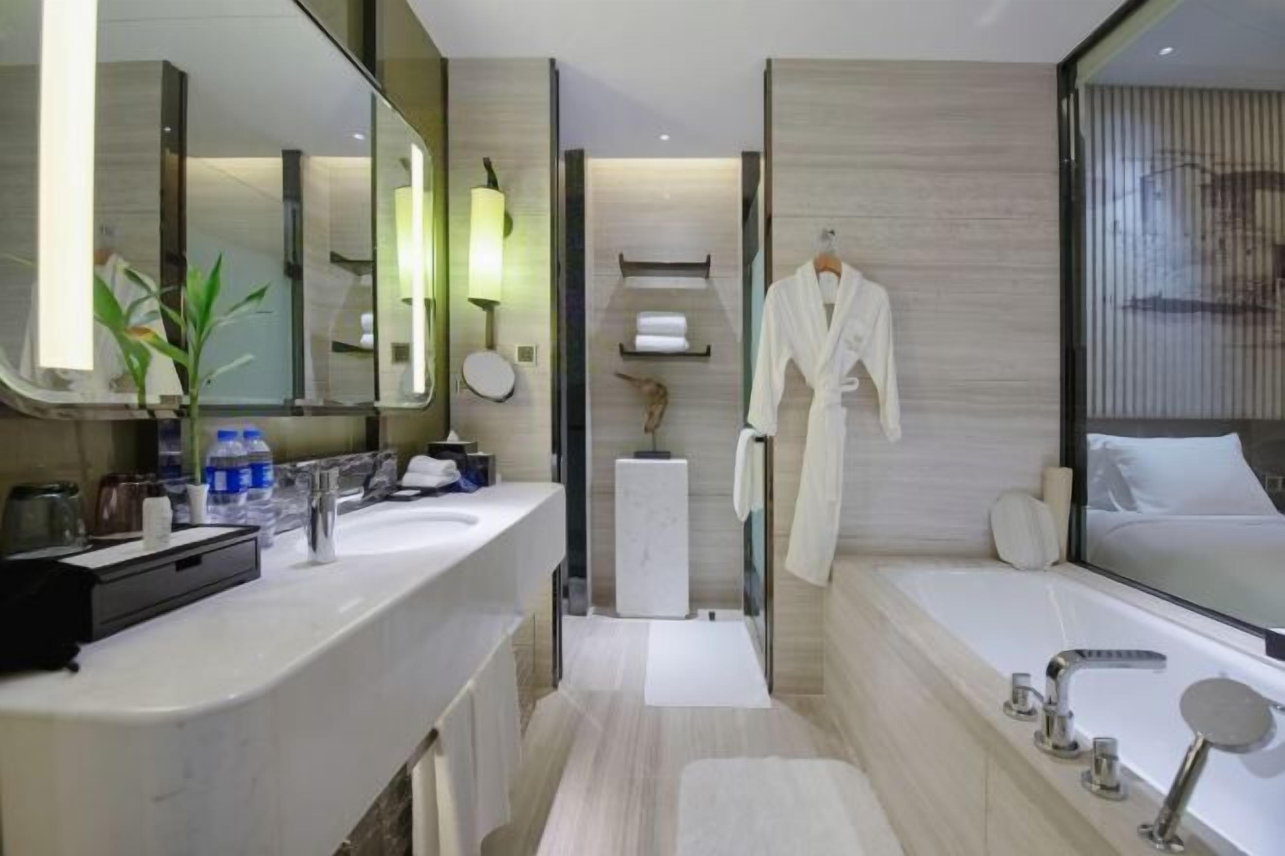 A modern bathroom with a large mirror, a bathtub, a vanity with a sink, and a towel rack.