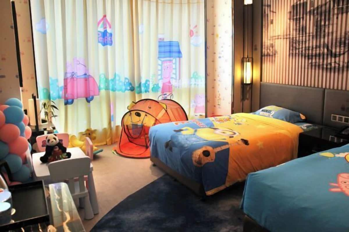 A children's room with two beds, a play tent, and a panda chair.