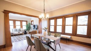 Tilava ruokailutila, jossa on puinen pöytä, tuolit ja koristeellinen kattokruunu.