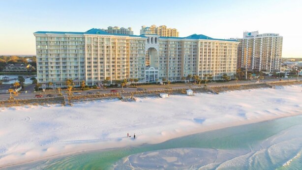 Un grand hôtel à étages, doté d’une cour intérieure et d’une plage avec une eau cristalline.