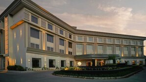 Un hotel moderno con fachada curva, ventanas amplias y una entrada ajardinada.