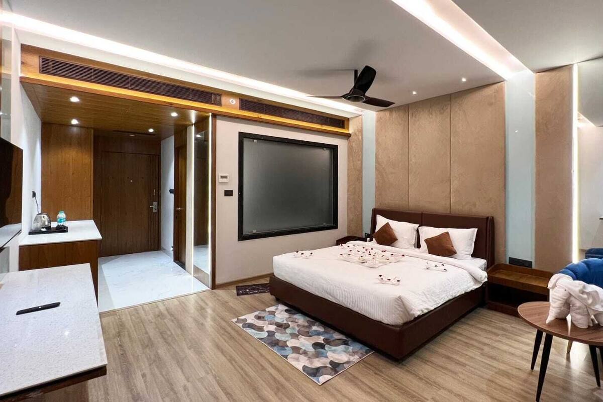 A modern hotel room with a large bed, a desk, a chair, and a TV.