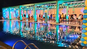 Zona junto a la piscina con fuente, mobiliario para sentarse e iluminación decorativa.