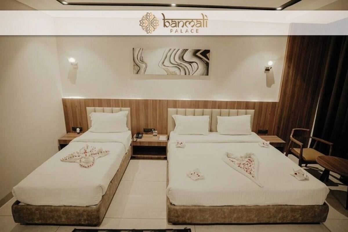 A hotel room with two beds, a wooden headboard, a wall-mounted artwork, and a sign reading "bancali palace".