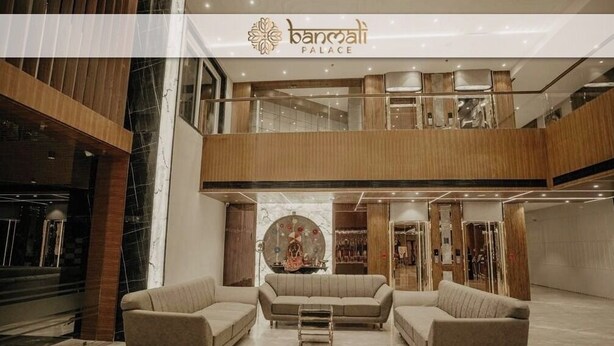 Un lobby espacioso con techo alto, un área de estar central y un piso superior visible con barandilla.