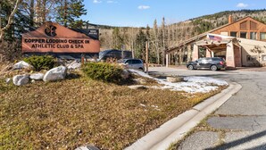 A sign for Copper Lodging Check-In, Athletic Club & Spa, with a parking area and a building with an American flag. - Gac217c1 (Copper Mountain)
