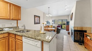 A kitchen with granite countertops, wooden cabinets, a dishwasher, and a dining area with a table and chairs. - Gac316c2 (Copper Mountain)