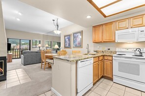 A modern kitchen with a built-in dishwasher, a stove, and wooden cabinets. - Greens at Copper #315 By Summit County Mountain Retreats (Copper Mountain)