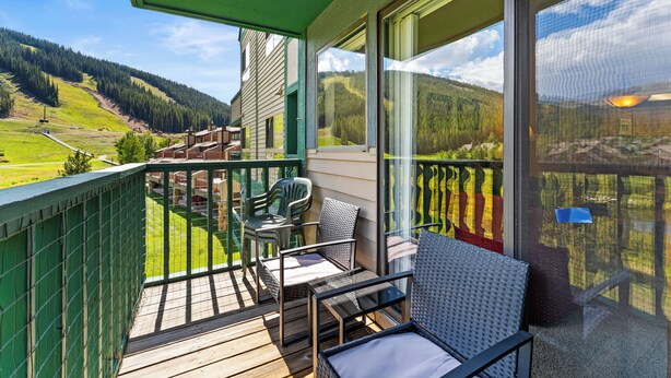 A balcony with a view of a mountainous landscape, wicker furniture, and a green railing. - Gac317c2 (Copper Mountain)