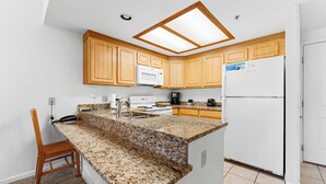 A kitchen with wooden cabinets, a granite countertop, a microwave, a coffee maker, and a refrigerator. - Gac317c2 (Copper Mountain)