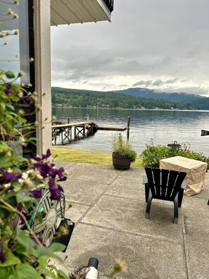 A patio with a view of a lake, a dock, and a chair.