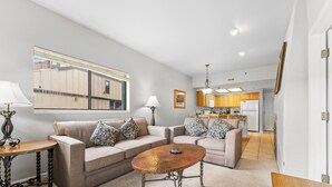 A living room with two sofas, a coffee table, and a dining area with wooden cabinets and a refrigerator. - Gac219c1 (Copper Mountain)