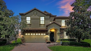 A two-story house with a garage, a front entrance with an arch, and a well-maintained lawn.