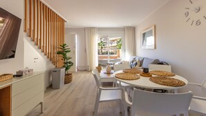 A modern living room with a dining area, featuring a staircase, a large window with a view, and a wall clock. - Beautiful home in Torre de la Horadada (Torre de la Horadada)