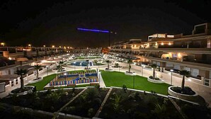 A hotel courtyard at night with multiple floors, a central pool, and landscaped gardens. - Beautiful home in Torre de la Horadada (Torre de la Horadada)
