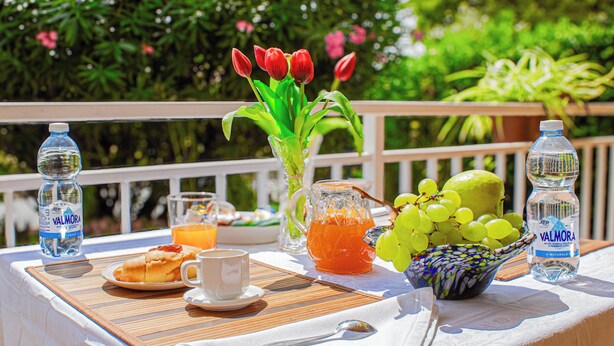 A breakfast table with water bottles, a pitcher of orange juice, a bowl of grapes, and a vase with red tulips. - Panoramic in the Hillside surrounded by greenery (Moncalieri)