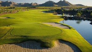 A golf course with a water hazard, sand bunkers, and a flagstick.