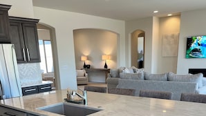A modern kitchen with a large island, stainless steel appliances, and a built-in dishwasher.
