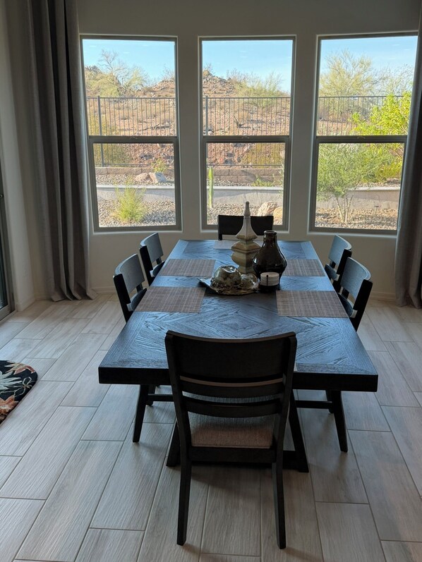 Un comedor con mesa y sillas, ventanas amplias con vistas a un paisaje desértico.