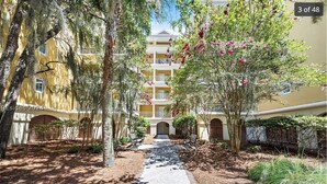 A courtyard with a pathway leading to a building with balconies.