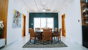 A spacious dining area with a high ceiling, modern furniture, and artwork on the walls.
