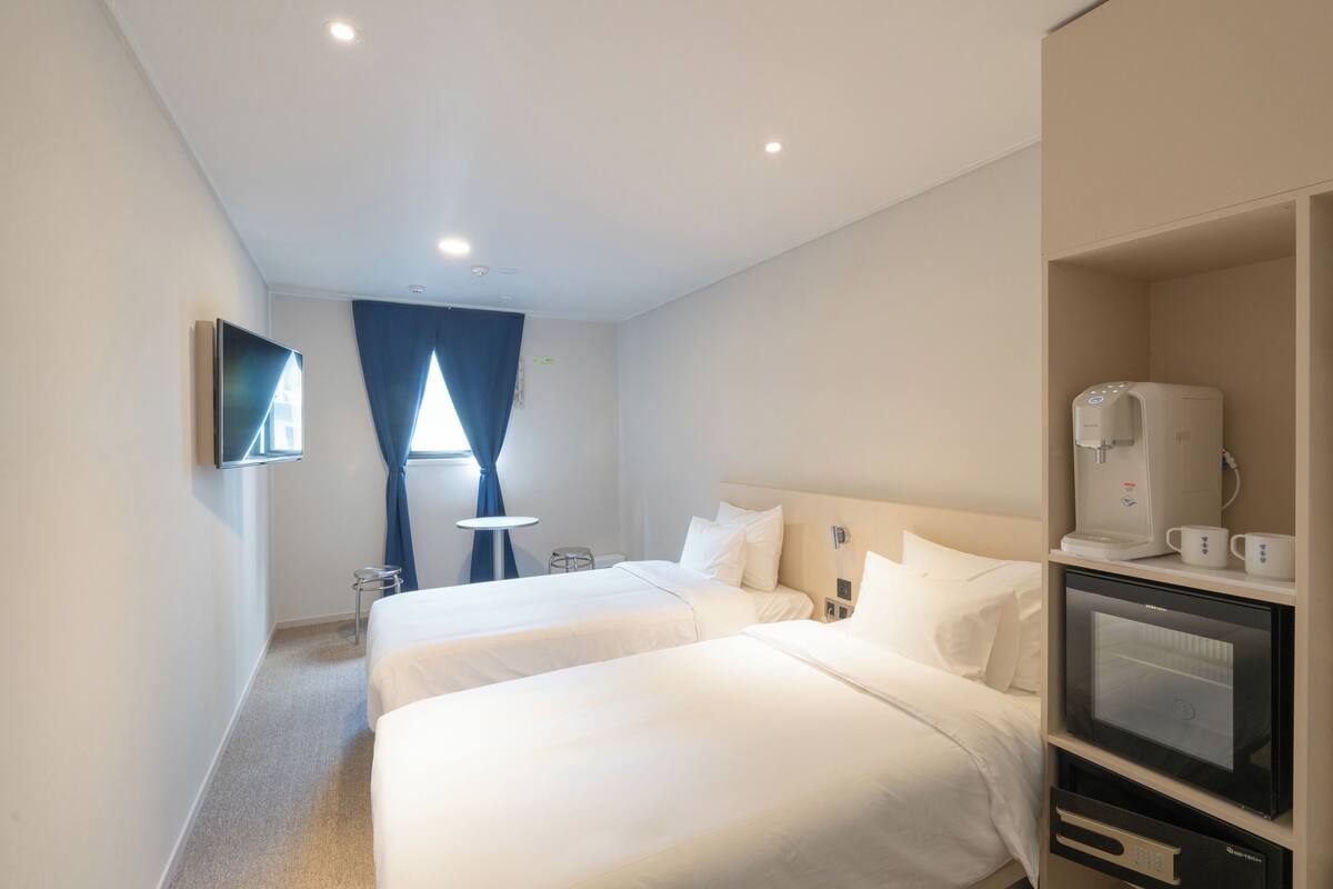 A hotel room with two beds, a coffee machine, and a TV.