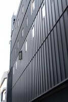 Un edificio moderno con fachada de listones verticales y numerosas ventanas.
