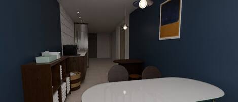 A hotel room with a large round table, a small seating area, a wardrobe, and a desk with a computer.